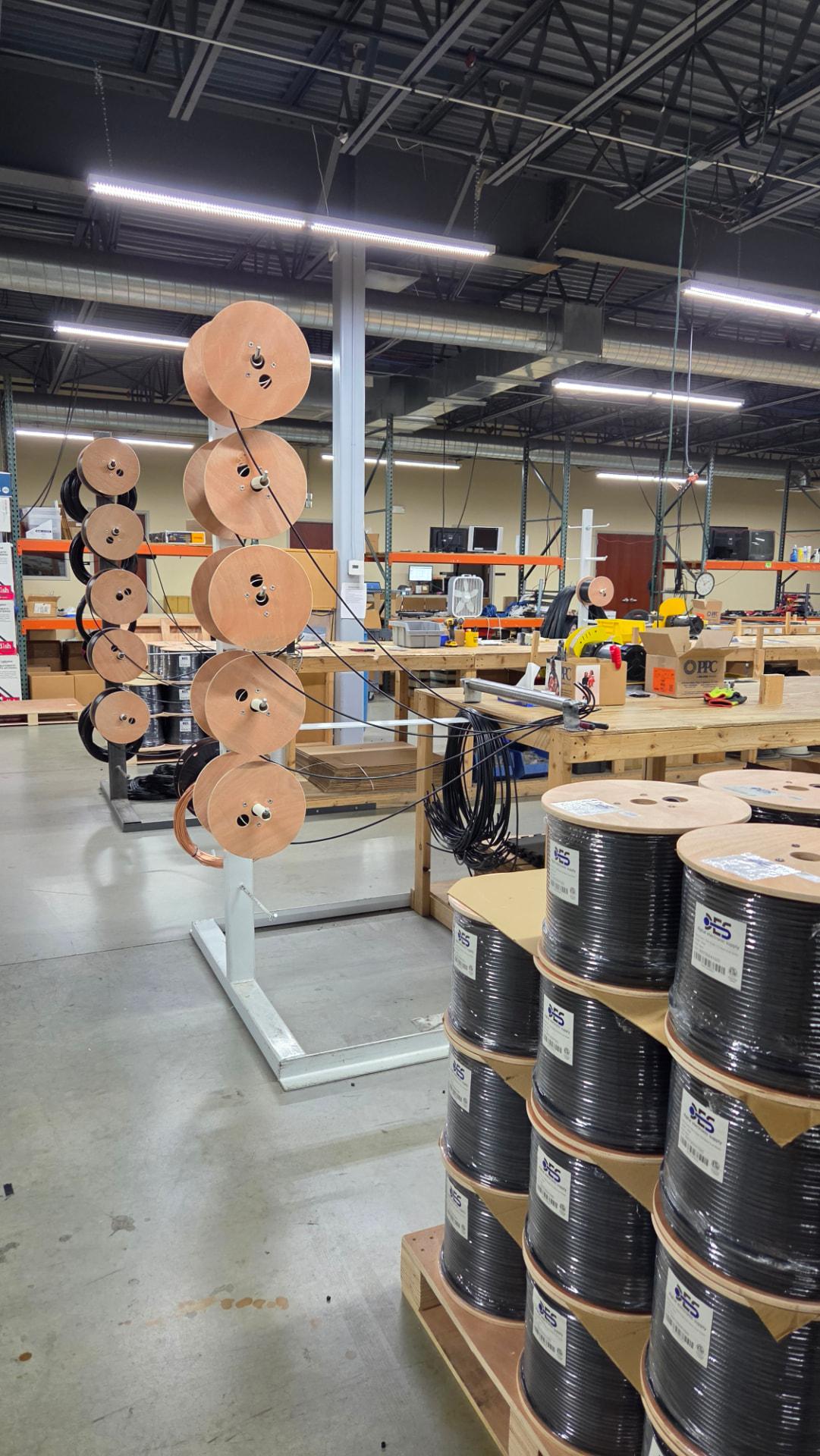 Reels of custom cable stored on dispensing racks in a warehouse